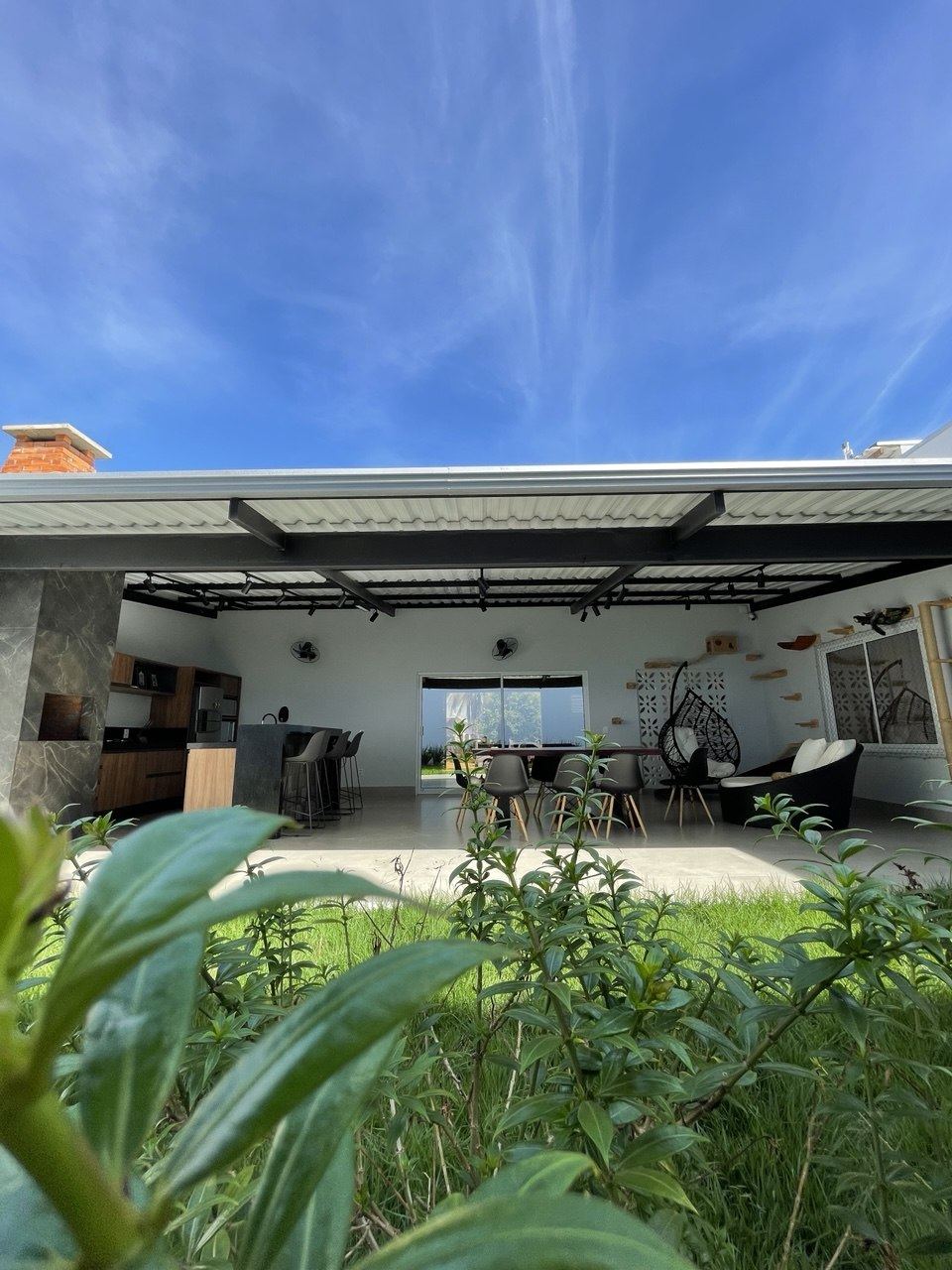 Área gourmet vista do jardim, com cobertura de telha sanduíche